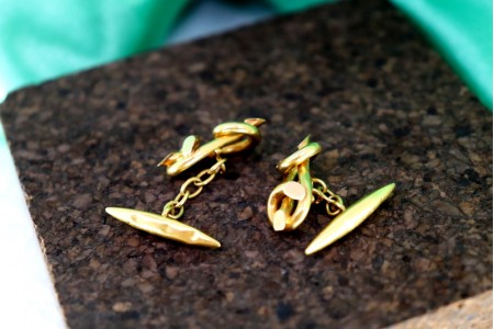 Botões de punho em ouro em formato de laço duplo.